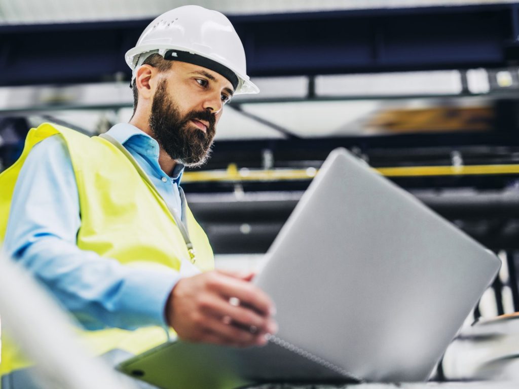 man in PPE looking at computer