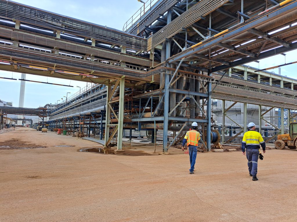 Two men in high vis walking across a mine site