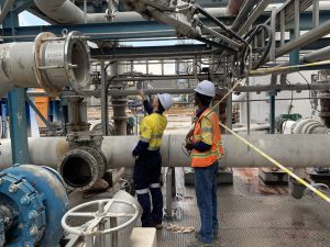 [3:48 pm] Andrew Hislop two men looking at pipes, valves and pumps on a mine site wearing high vis, discussing how to make logic for its automatic control