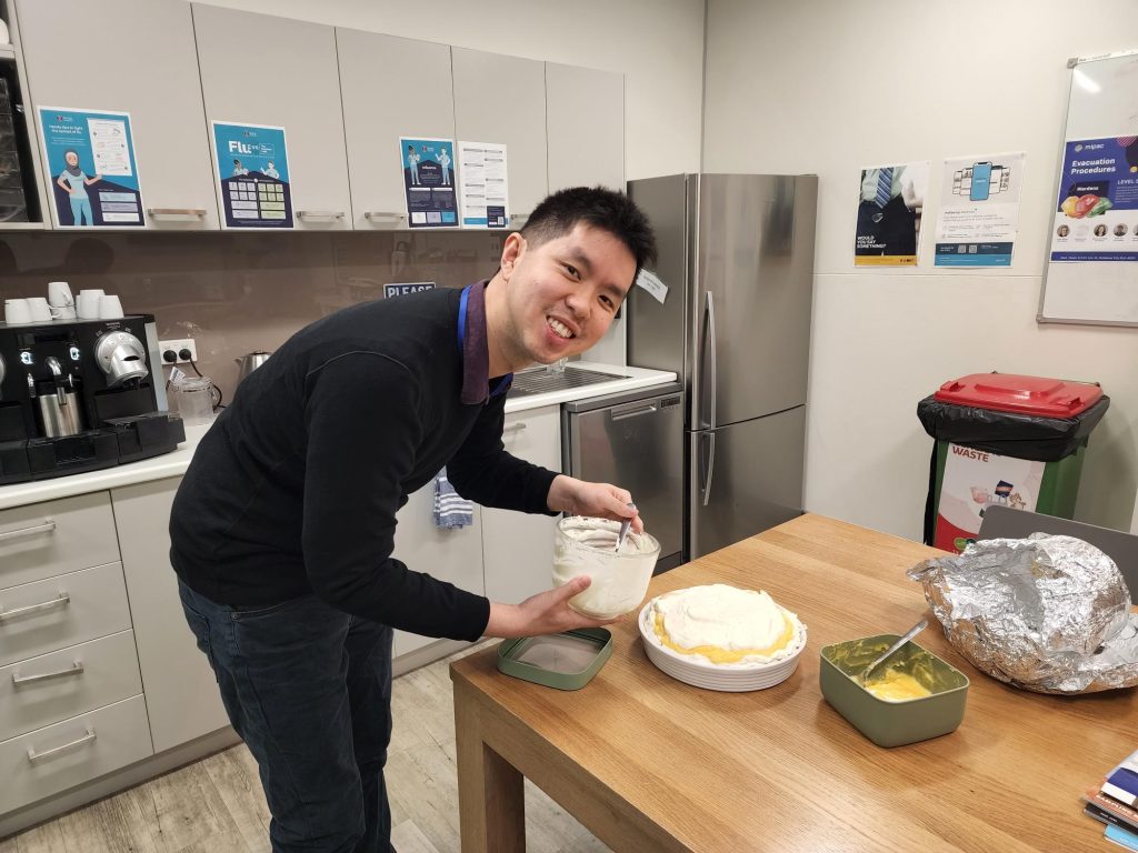 Man decorating a cake in an office kitchen