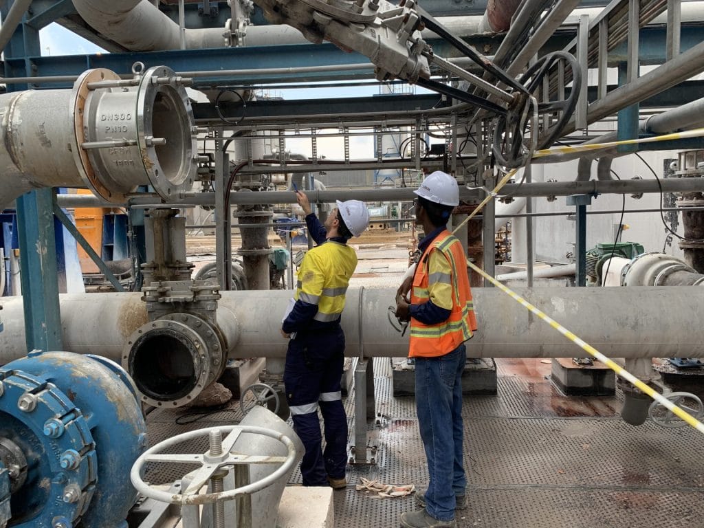 Two men in high vis clothing inspecting a pipe
