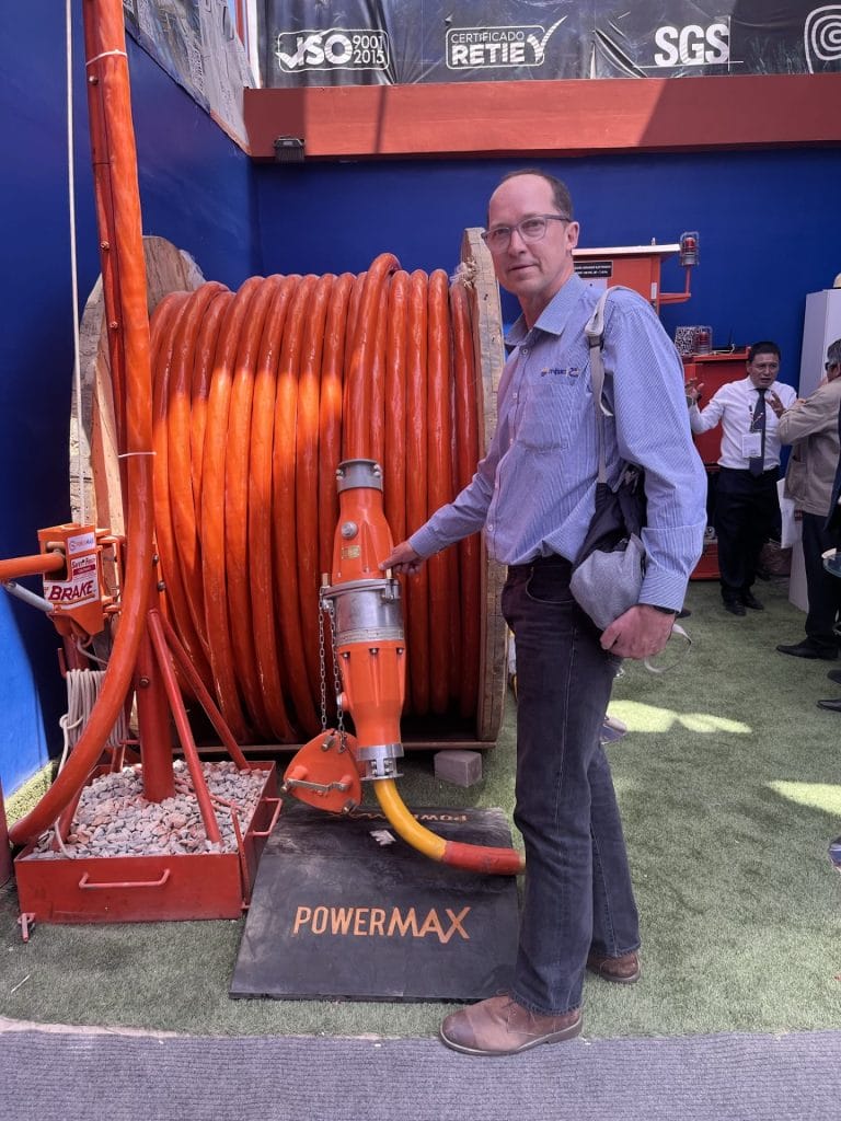 Man standing in front of a large orange hose, holding it.