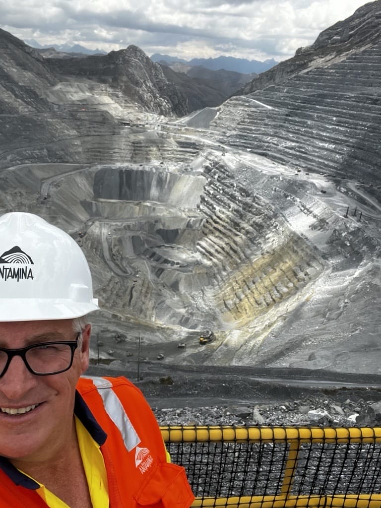 Man in high vis standing in front of an open pit mine