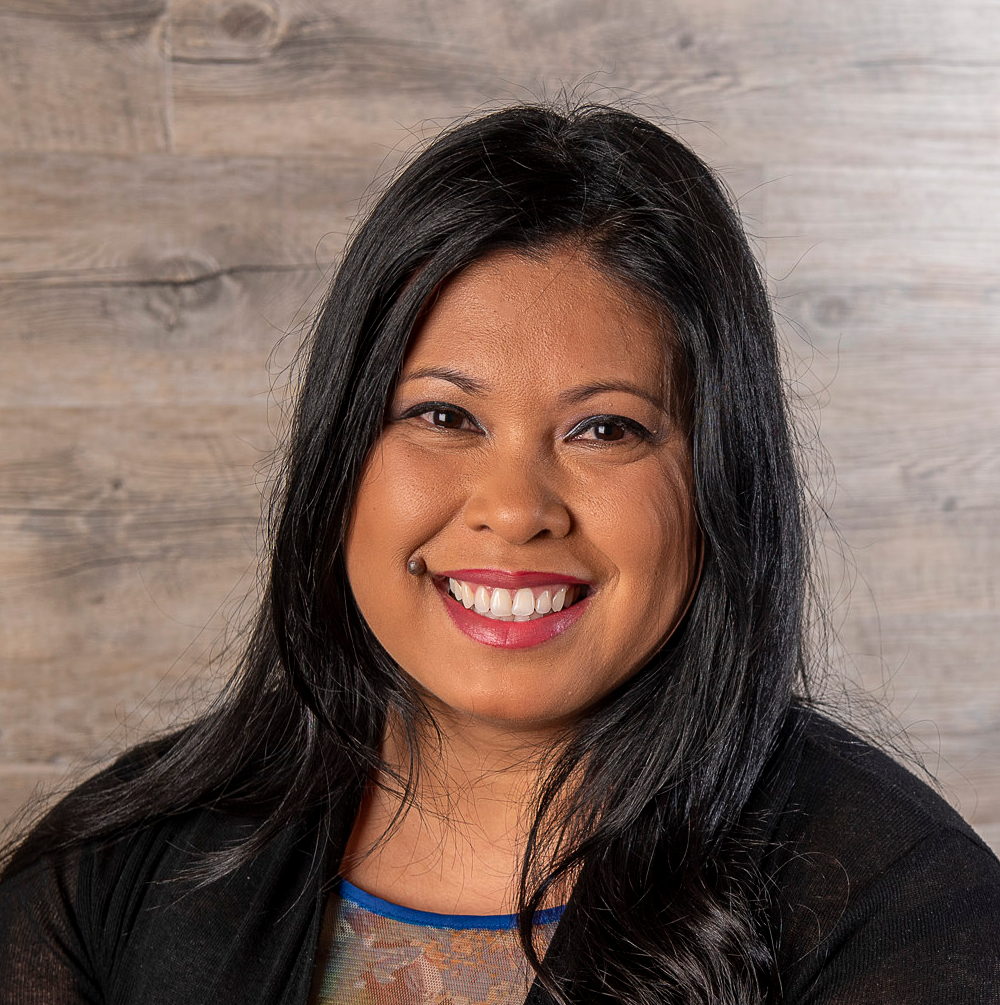 Profile photo of a dark-haired woman on a timber background