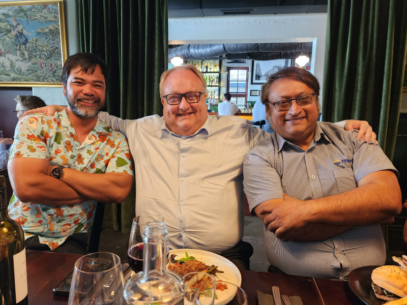 Three smiling men (Virgilio Bay, Sandro Cella and Raja Ganguli from the Mipac Perth office) enjoying a lunch in a restaurant